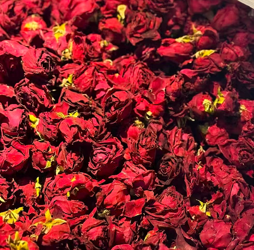 A dense cluster of dried red roses filling the frame, with deep crimson petals and small hints of yellow-green at the centers.