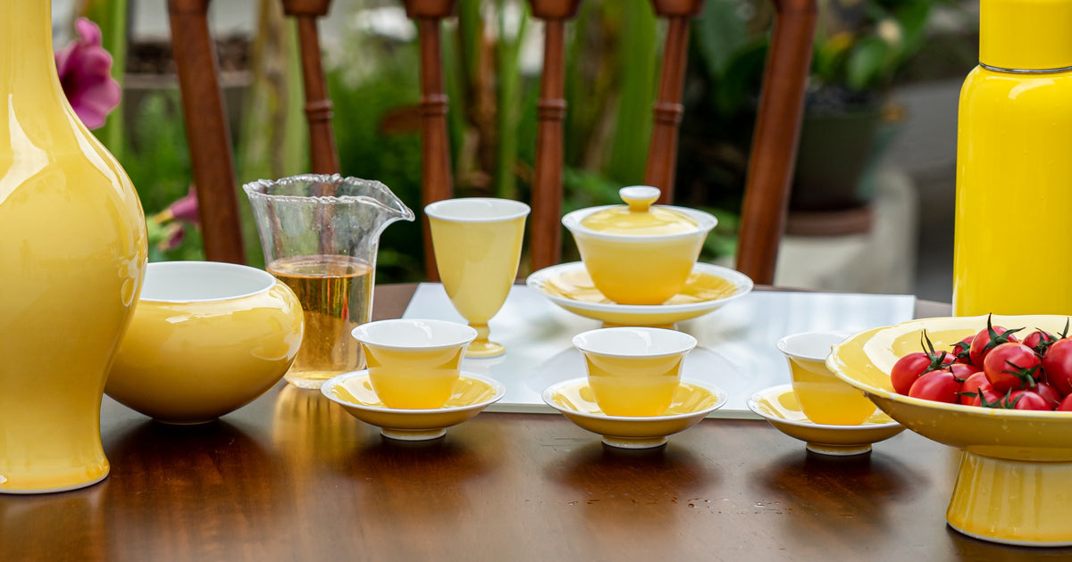 Yellow ceramic tea set on a table with a blurred outdoor background