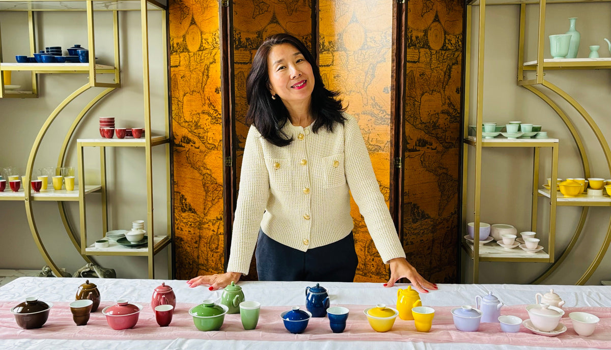 Woman standing behind a table with ceramic items in a decorative setting